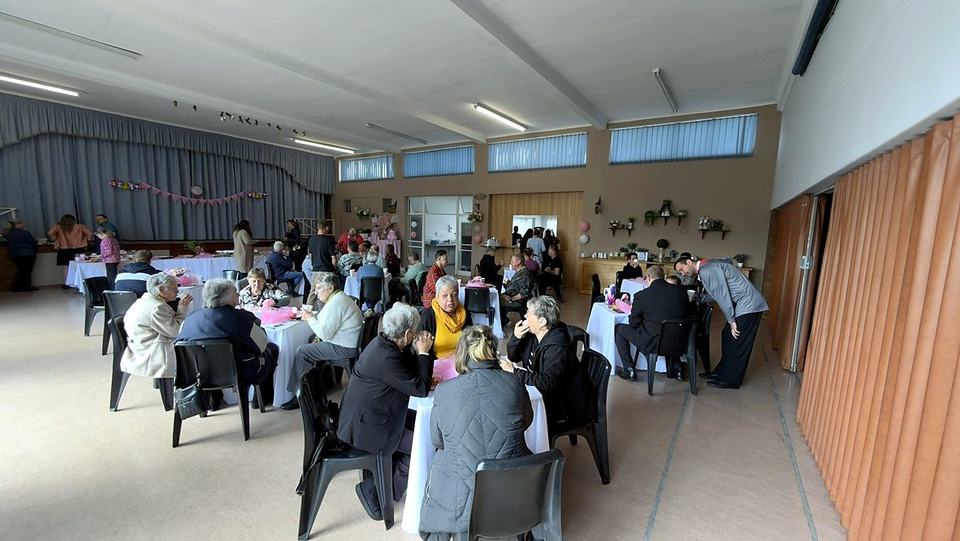 Die gemeente om gedekte tafels in die saal, in gesprek